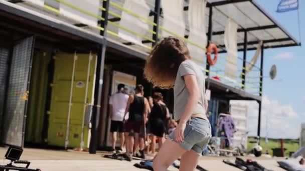 МОСКВА, РОССИЯ - 12 июля 2019 года: Молодая женщина в серой футболке и с длинными волосами пытается стоять на доске для равновесия — стоковое видео