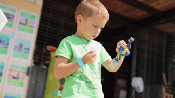 Moskva, Ryssland - 12 juli 2019: Liten pojke i grön t-shirt och liten flicka i rosa t-shirt lek med plastleksaker. — Stockvideo