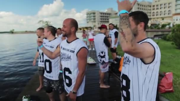 MOSCÚ, RUSIA - 12 DE JULIO DE 2019: Grupo de hombres jóvenes en camisetas blancas se paran en el muelle y saludan con las manos — Vídeos de Stock