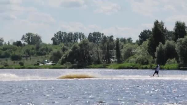 Moskau, russland - 12. juli 2019: sportlicher kerl fährt spielerisch wasserski mit geschwindigkeit hinter boot auf engem fluss — Stockvideo