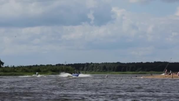 MOSCÚ, RUSIA - 12 DE JULIO DE 2019: Hombre de esquí acuático paseos de esquí acuático a velocidad siguiendo barco a motor a lo largo del río — Vídeos de Stock