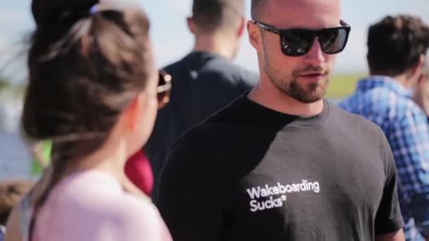 Moskva, Rusko - 12. července 2019: Roztomilý plešatý vousáč ve slunečních brýlích něco vysvětluje krásné brunetce — Stock video