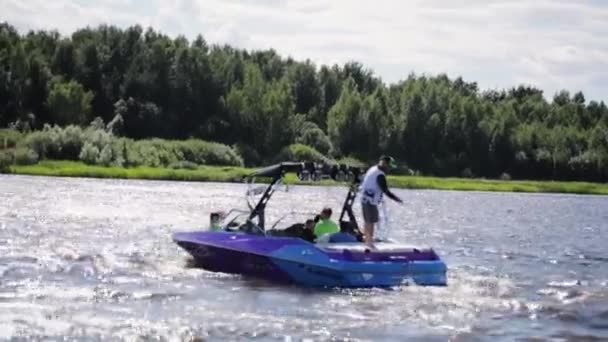 Moskau, russland - 12. juli 2019: violettes motorboot voller menschen darin schwimmt an sonnigen sommertagen im fluss. — Stockvideo