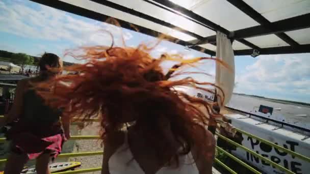MOSCÚ, RUSIA - 12 de julio de 2019: Dos hermosas mujeres jóvenes con el pelo largo bailan dinámicamente en el escenario en el resort — Vídeo de stock