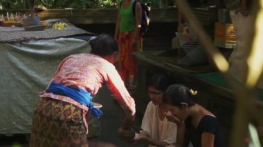 Bali, Endonezya - 22 Nisan 2018: Köyde yaşlı Asyalı kadınlar yüzlerini ve başlarını yıkamak için kızların ellerine su döker.