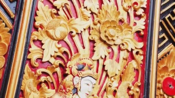 Bali, Indonesien - 22 april 2018: Träyta med handhuggen bild av kvinnan och symboler för buddhismen. — Stockvideo