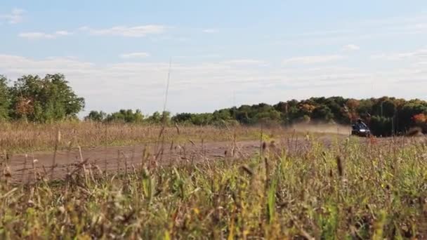 Quadrocycle with two men is extremely riding on dusty offroad with among grasses — Stock Video