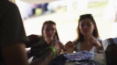 Genç terzi kadın müşterilerle konuşur.