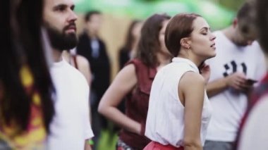 Genç esmer kız, beyaz gömlekli, kalabalıkta dans ediyor.