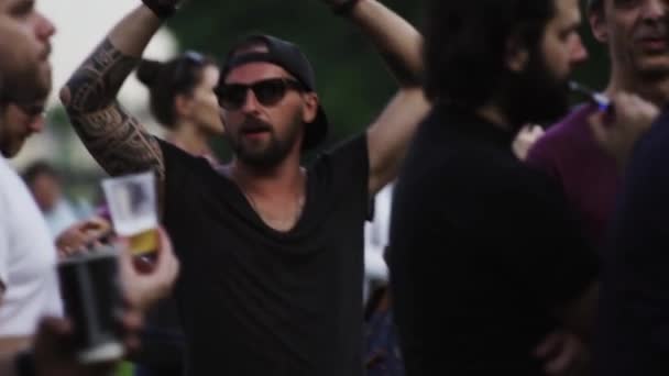 Обожнений чоловік з татуюваннями танцює в натовпі людей на літній мю — стокове відео