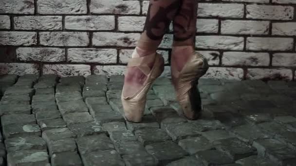Legs in golden pointe shoes are actively dancing ballet next to white brick wall — Stock Video
