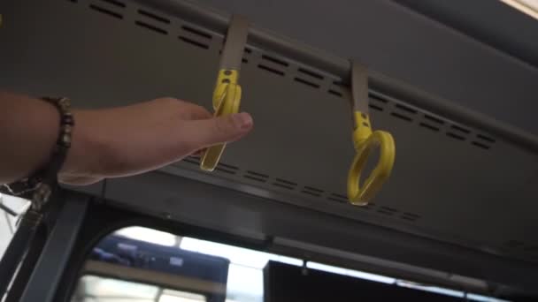 Mans mão com pulseira segura no aperto de mão amarelo dentro de um ônibus . — Vídeo de Stock