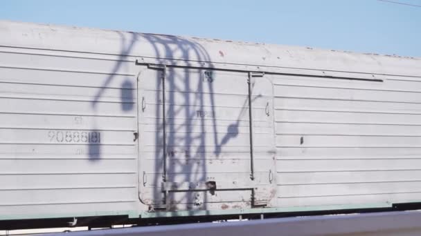 Ланцюг білих вантажних вагонів рухається повільно на залізниці і проходить в сонячний день — стокове відео