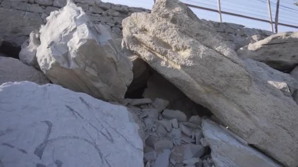 Szürke sziklák és kövek halmait szedik össze a part szélén, közeledő hullámokkal. — Stock videók