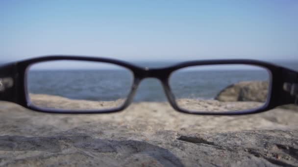 Vista attraverso gli occhiali di costa con onde che cadono sulla spiaggia di sabbia nella giornata di sole — Video Stock