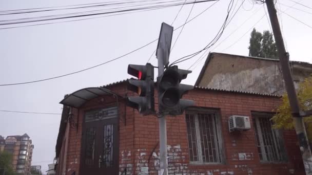 Çevresindeki binalar ve ağaçlarla caddede renk değiştiren trafik ışığı. — Stok video