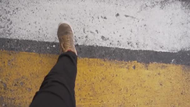 Alguém vestido com calças pretas e tênis marrom está andando na travessia da zebra . — Vídeo de Stock