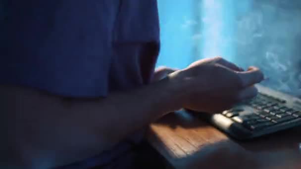 Camera draait rond man in t-shirt die mobiele telefoon gebruikt en rookt in donkere kamer — Stockvideo