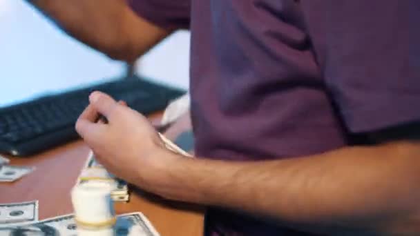 L'uomo in t-shirt viola butta via attivamente il pacchetto di banconote in dollari USA nella stanza buia . — Video Stock