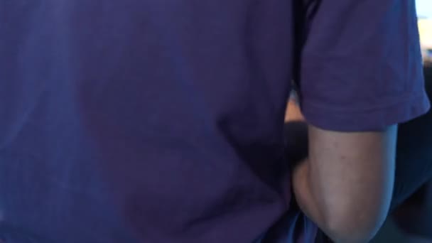 男性が積極的に彼のスマートフォン上でアプリをサーフィン紫色のTシャツを着てのビュー. — ストック動画