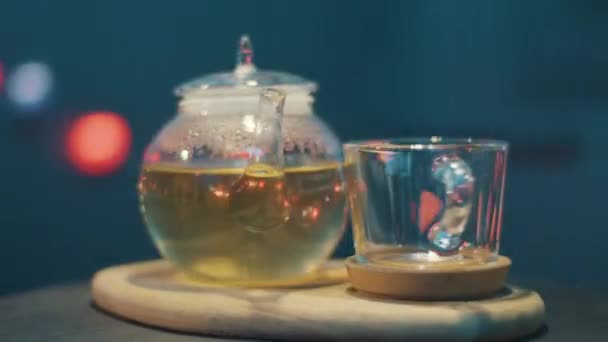 Cute glass teapot and glass cup on table with actively rotating camera around. — Stock Video