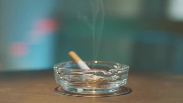 Processus de rotation de cendrier en verre élégant avec cigarette brûlante placée à l'intérieur .