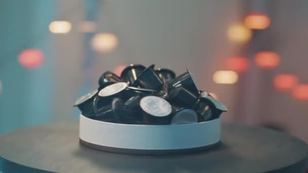 Isolierter runder Teller mit mehreren Kaffeemaschinen-Kapseln auf dunklem Tisch. — Stockvideo