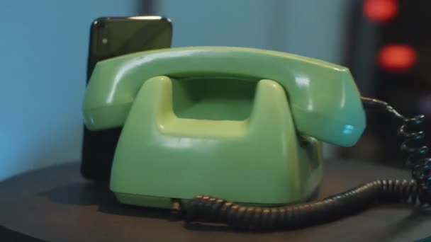 Camera draait rond groene vintage telefoon en zwarte moderne smartphone op tafel — Stockvideo