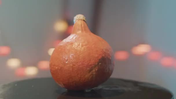 Camera beweegt rond geïsoleerde oranje ronde-vormige pompoen op zwarte tafel. — Stockvideo