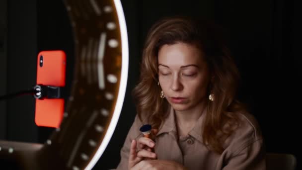 Femme mûre tire tutoriel beauté en face de la lumière de l'anneau dans la chambre noire . — Video