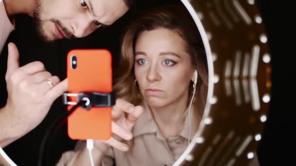Männliche und weibliche Beauty-Bloggerin voreingestelltes Smartphone vor dem Ringlicht. — Stockvideo