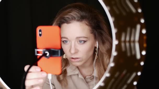 Fiatal szőke nő szépség blogger birtokol narancs smartphone és beszél. — Stock videók