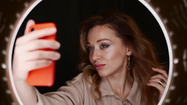 Vrouwelijke make-up kunstenaar houdt smartphone voor ring licht en neemt selfie. — Stockvideo