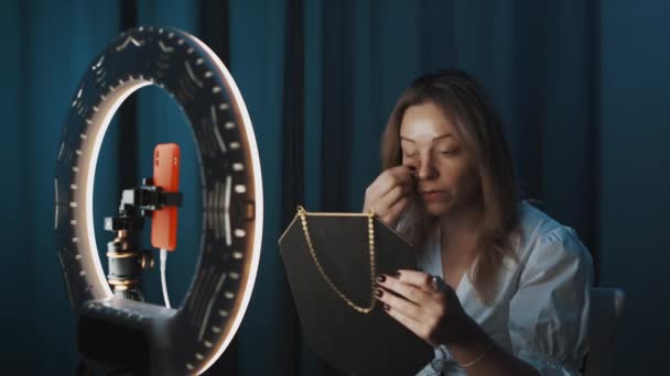 Attractive woman is doing makeup in front of ring light, shooting beauty vlog. — Stock Video