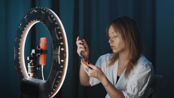 Loira jovem fêmea coloca o produto de cosméticos na pele da mão durante a vlog de beleza — Vídeo de Stock