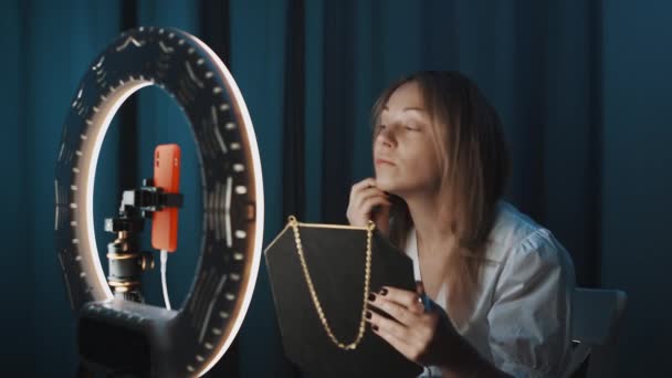 Genç bir kadın online video yayını sırasında halka ışığının önünde makyaj yapıyor. — Stok video