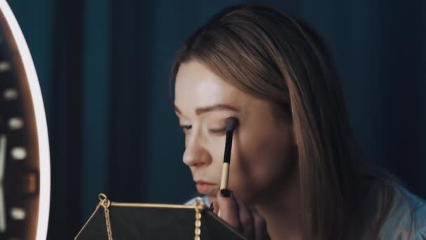 Jeune femme séduisante blogueur de mode fait ses yeux avec une grande brosse cosmétique . — Video