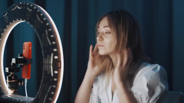 Bastante caucásico mujer maquillaje artista está haciendo maquillaje en frente de la luz del anillo . — Vídeos de Stock