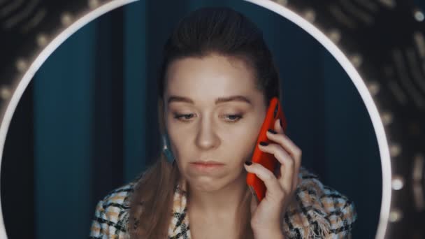 Vue à travers la lumière anneau de la jeune femme vlogger mode parlant au téléphone . — Video