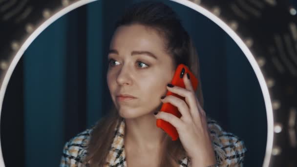 Mira a través de la luz del anillo a la mujer linda blogger belleza hablando en el teléfono inteligente . — Vídeo de stock