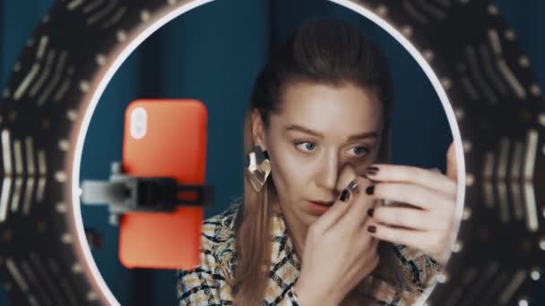 Ung kvinnlig skönhet bloggare gör contouring framför ring ljus för kanal. — Stockvideo