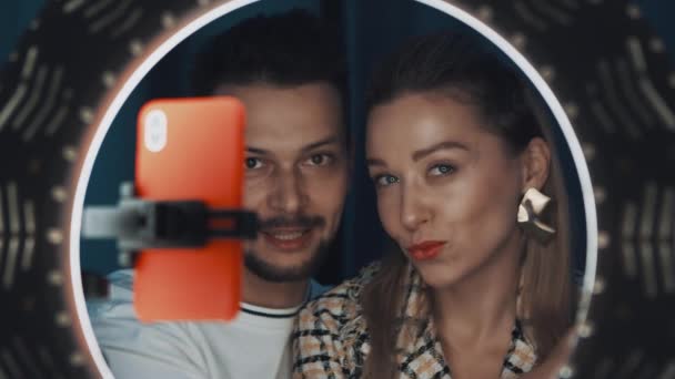 Uśmiechnięta brunetka mężczyzna i kobieta blogger uroda rozmawiać przed ring light. — Wideo stockowe