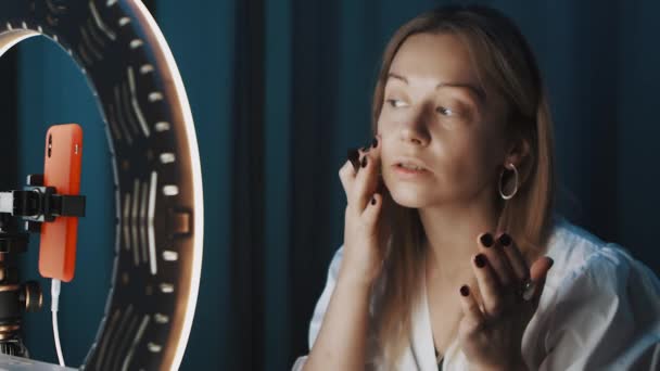 Красивая женщина-блоггер красоты наносит макияж перед кольцом света онлайн . — стоковое видео