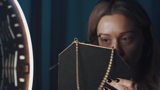 Woman beauty vlogger fills in her brows with small brush in front of ring light. — Stock Video