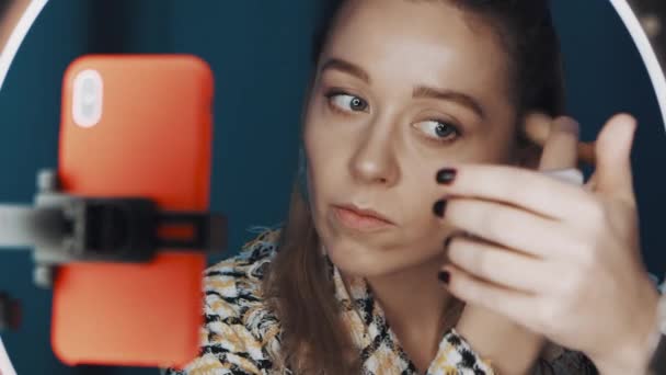 Blogger de moda rubia joven está contorneando la cara frente a la luz del anillo . — Vídeo de stock