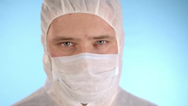 白い保護スーツ 医療用マスク 青の背景にゴム手袋の白人男性は 赤い液体と碑文と手のテストチューブに保持2019 Ncvをテストチューブを示し その後 カメラへのテストチューブを示しています — ストック動画
