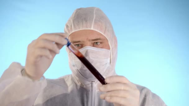 보호용 양복을 의료용 마스크 파란색 배경에 고무장갑 액체가 들어간 시험관을 — 비디오