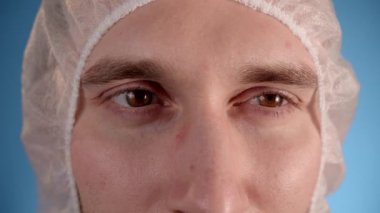 Beyaz önlüklü, mavi önlüklü beyaz erkek laboratuvar teknisyeni gözlük ve koruyucu maske takıyor. Kapat.