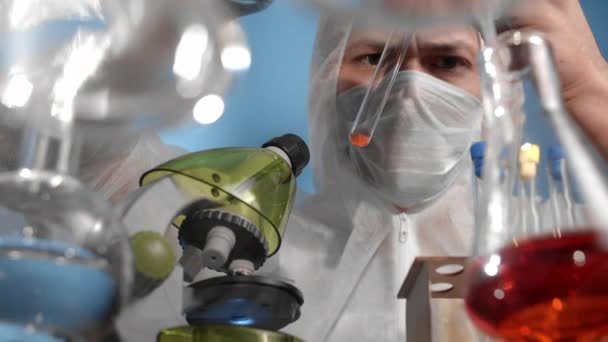 의료용 마스크와 보호용 작업복을 사용하는 과학자들 피펫에서 비커로 액체를 떨어뜨리고 — 비디오