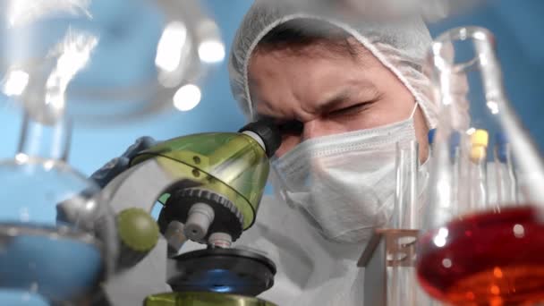 의료용 마스크와 보호용 수트를 착용하고 과학자가 현미경을 들여다보며 카메라에 무엇인가를 — 비디오